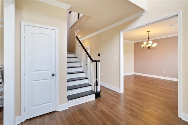 staircase with baseboards, ornamental molding, a chandelier, and wood finished floors