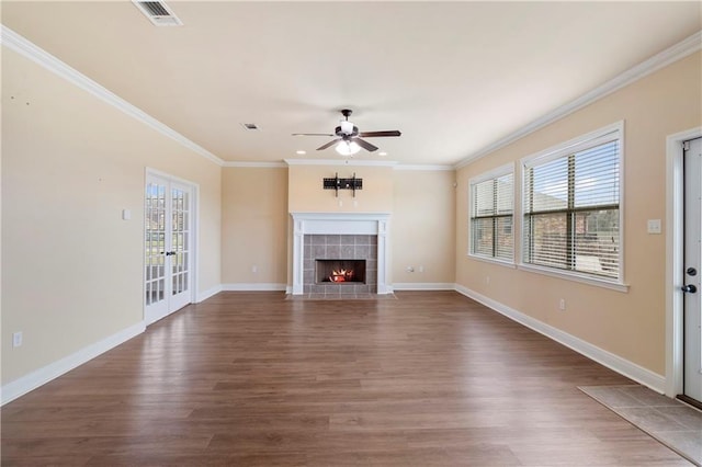 unfurnished living room with a healthy amount of sunlight, visible vents, a tiled fireplace, and wood finished floors