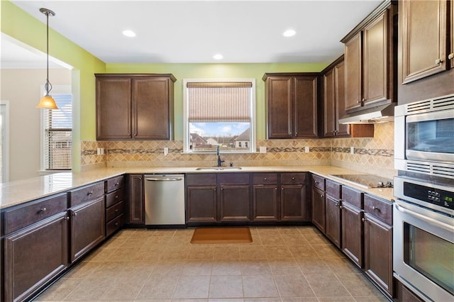 kitchen with dark brown cabinetry, stainless steel appliances, light countertops, under cabinet range hood, and a sink