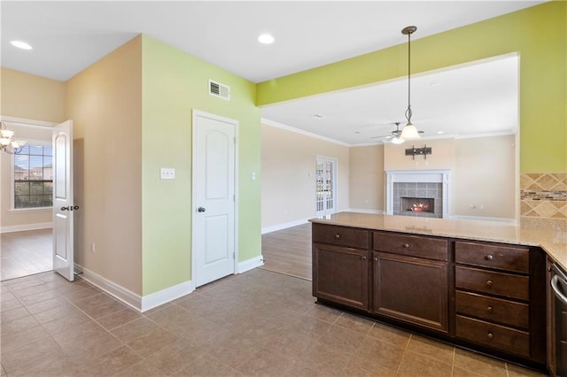 kitchen with visible vents, baseboards, dark brown cabinets, hanging light fixtures, and a tiled fireplace