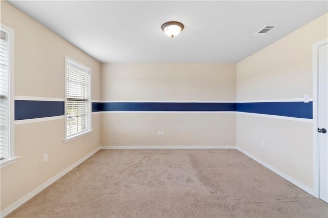 carpeted spare room with visible vents and baseboards