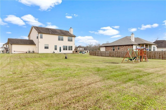 back of house featuring a yard, a playground, fence, and a chimney