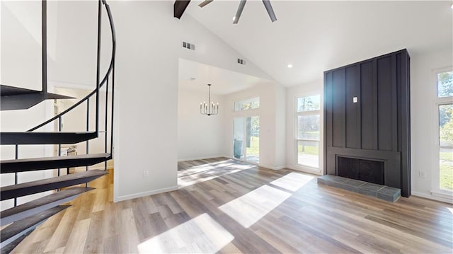 unfurnished living room featuring stairs, plenty of natural light, visible vents, and light wood-style floors