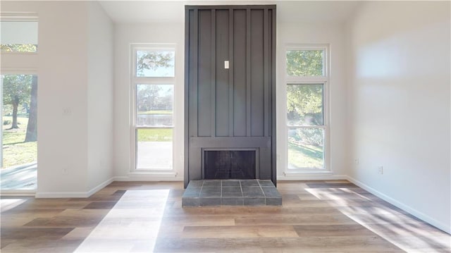 interior space featuring a tiled fireplace, baseboards, and wood finished floors