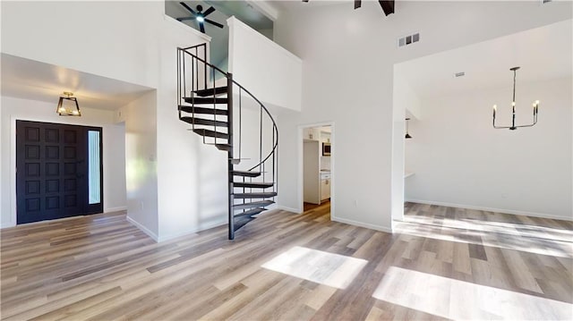 entrance foyer featuring light wood-style flooring, visible vents, baseboards, stairs, and an inviting chandelier