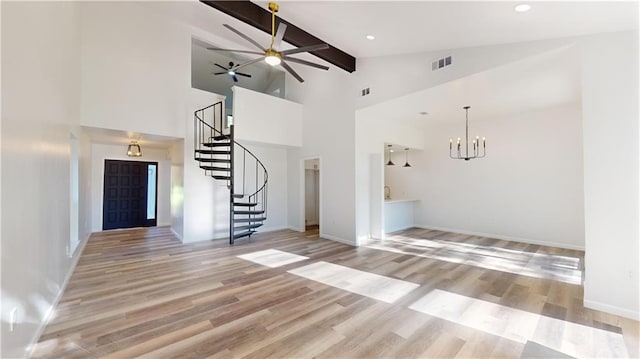 unfurnished living room with beam ceiling, visible vents, light wood-style flooring, and stairs