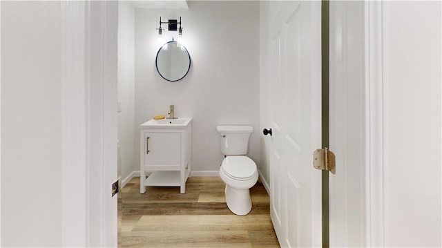 bathroom with baseboards, vanity, toilet, and wood finished floors