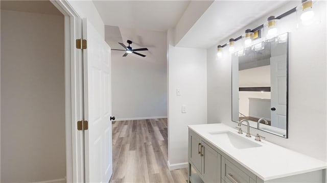 bathroom with baseboards, a ceiling fan, wood finished floors, and vanity