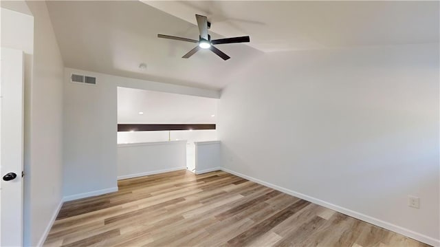 unfurnished room featuring lofted ceiling, wood finished floors, visible vents, baseboards, and a ceiling fan