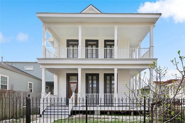 view of front of house with a fenced front yard, covered porch, and a balcony