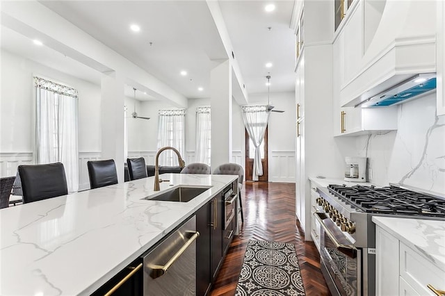 kitchen with stainless steel appliances, custom range hood, a sink, and light stone counters