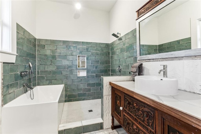 full bathroom featuring vanity, a soaking tub, a tile shower, and tile walls