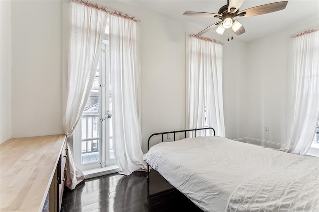 bedroom with dark wood-type flooring, multiple windows, and access to exterior