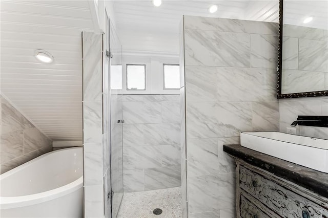 bathroom with a freestanding tub, a shower stall, tile walls, and a sink