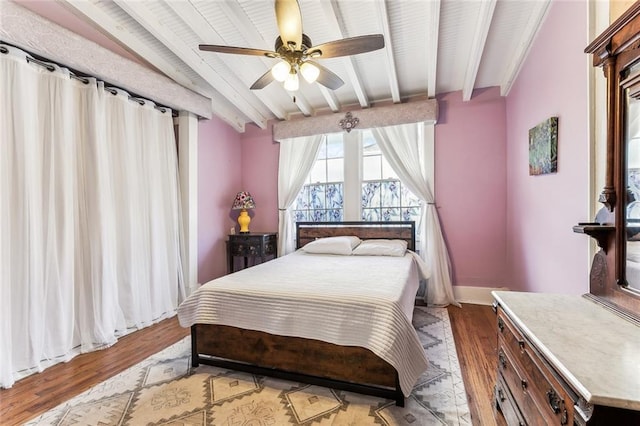 bedroom featuring light wood-type flooring, baseboards, a ceiling fan, and beam ceiling