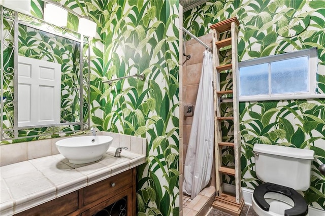 bathroom with toilet, wallpapered walls, vanity, and a stall shower