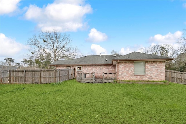 rear view of house featuring a yard, brick siding, a fenced backyard, and a wooden deck