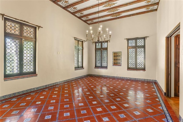 unfurnished room featuring plenty of natural light, baseboards, a towering ceiling, french doors, and a chandelier