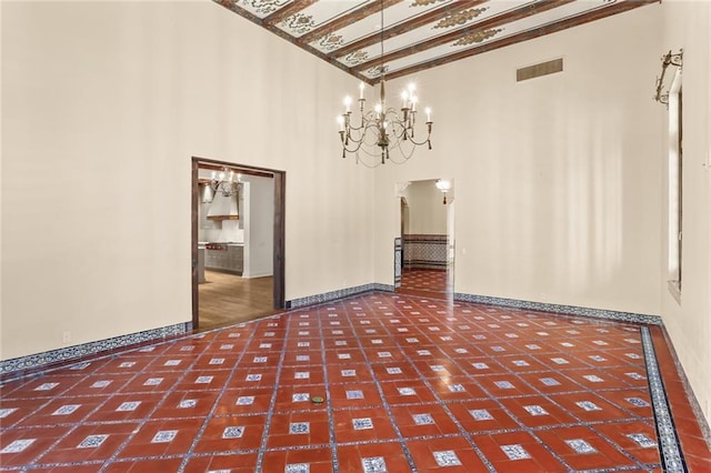 unfurnished dining area with arched walkways, a notable chandelier, a high ceiling, visible vents, and baseboards