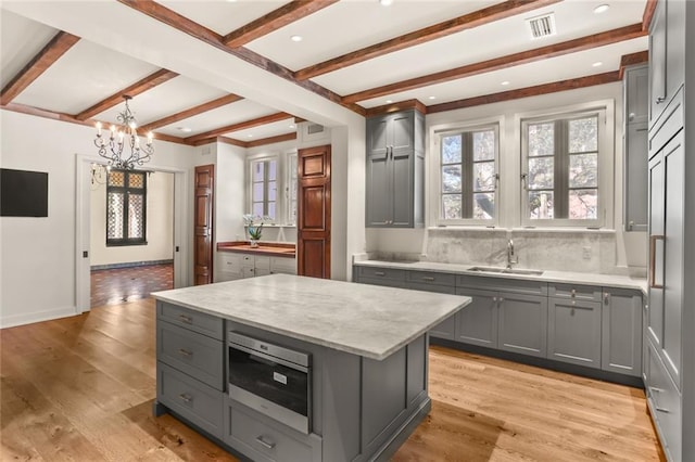 kitchen with light wood-style floors, a sink, visible vents, and gray cabinetry