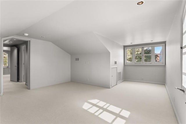 additional living space featuring lofted ceiling, plenty of natural light, carpet flooring, and visible vents