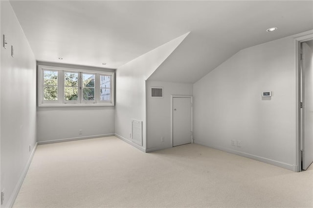 additional living space featuring carpet, visible vents, vaulted ceiling, and baseboards