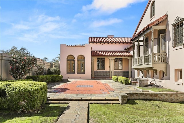 back of house featuring a tile roof and stucco siding