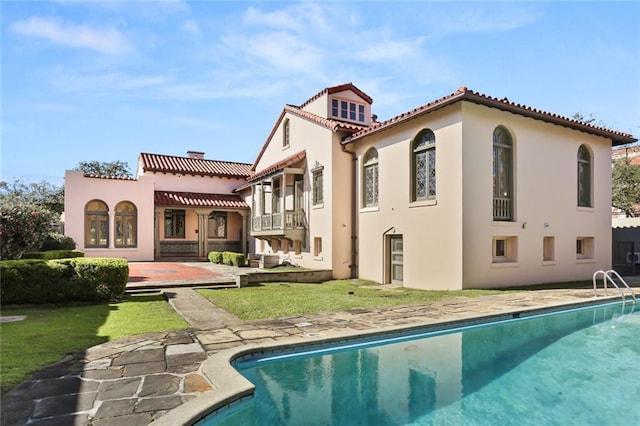 back of house featuring a yard, a patio, stucco siding, an outdoor pool, and a tiled roof