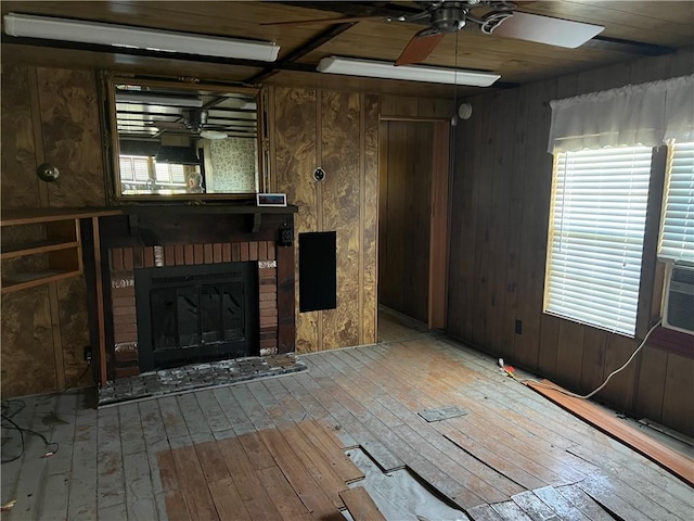 unfurnished living room with light wood-type flooring, a healthy amount of sunlight, and wood walls