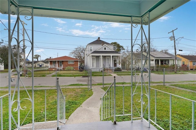 view of yard with covered porch, a fenced front yard, and a residential view