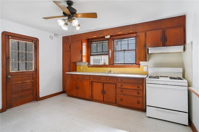 kitchen with gas range gas stove, light floors, light countertops, a sink, and under cabinet range hood