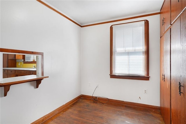 empty room with crown molding, dark wood finished floors, and baseboards