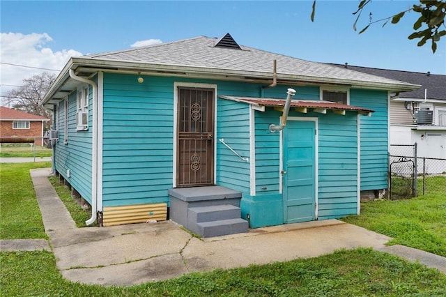 view of front facade featuring a front yard, roof with shingles, fence, and entry steps