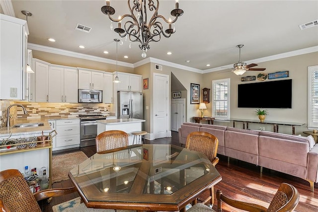 dining space with dark wood-style floors, crown molding, visible vents, and a ceiling fan