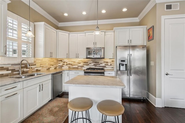 kitchen featuring stainless steel appliances, hanging light fixtures, a sink, and visible vents