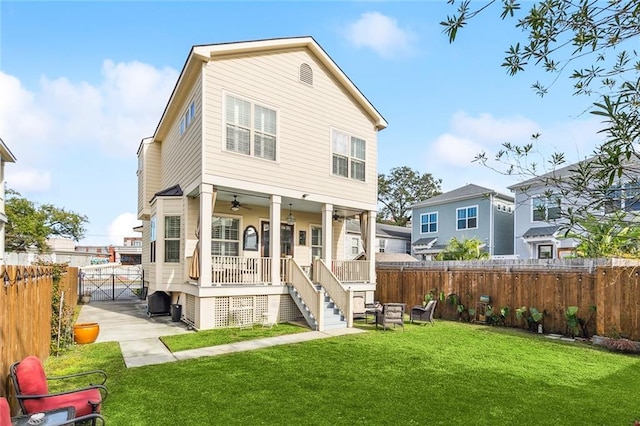 rear view of property with a ceiling fan, a lawn, a fenced backyard, covered porch, and a gate