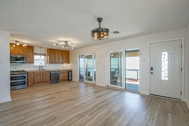 kitchen featuring stainless steel appliances, a sink, visible vents, light countertops, and light wood finished floors