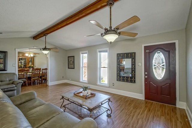 living room featuring vaulted ceiling with beams, a healthy amount of sunlight, baseboards, and light wood-style floors