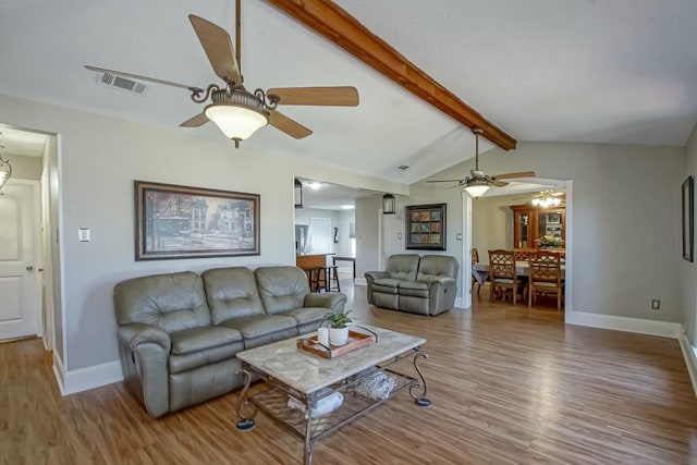 living room with visible vents, vaulted ceiling with beams, baseboards, and wood finished floors