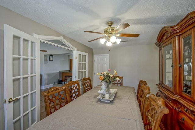 dining area with french doors, ceiling fan, and a textured ceiling