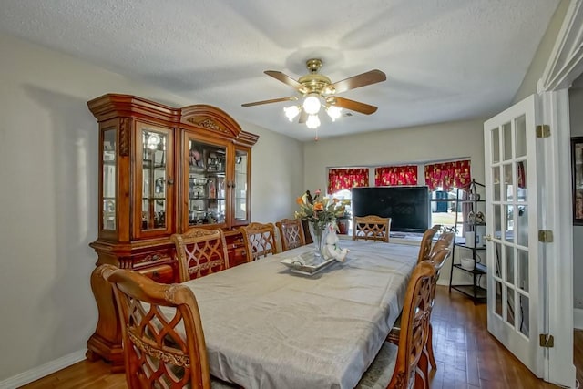 dining room featuring baseboards, a textured ceiling, a ceiling fan, and dark wood-style flooring