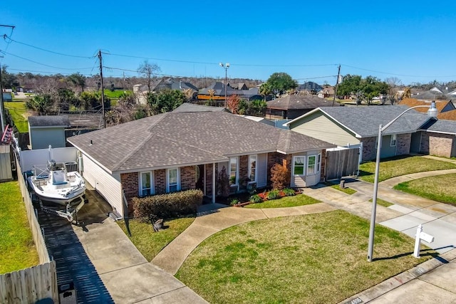 single story home featuring concrete driveway, brick siding, a front yard, and a residential view