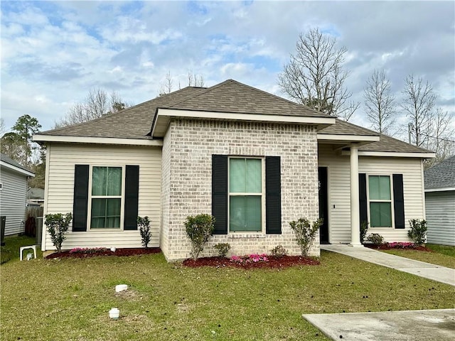 view of front facade featuring a front yard, brick siding, and roof with shingles