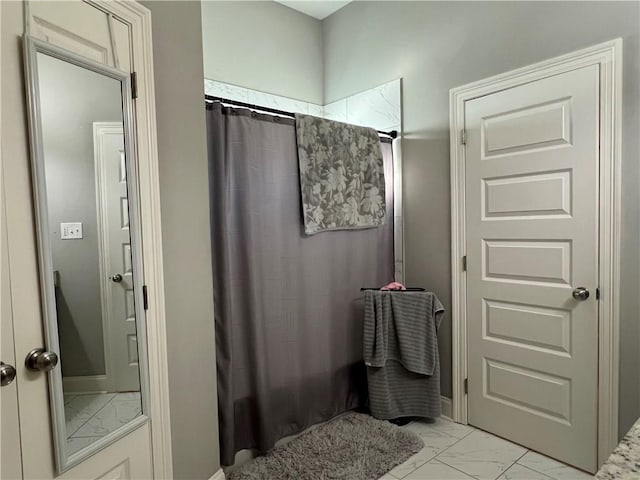 full bath with marble finish floor and a shower with curtain