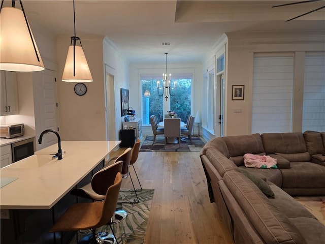 interior space featuring crown molding, visible vents, light wood finished floors, and a chandelier