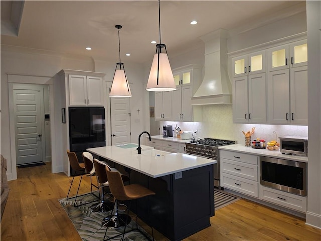 kitchen featuring stainless steel appliances, custom range hood, backsplash, white cabinetry, and a sink