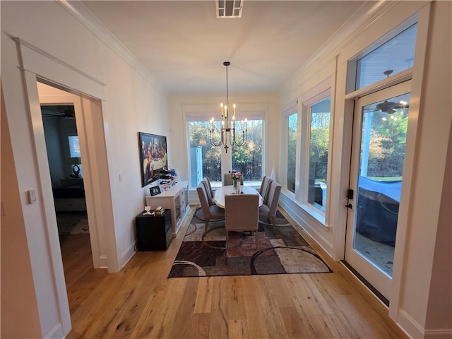 dining area with crown molding, visible vents, an inviting chandelier, light wood-type flooring, and baseboards