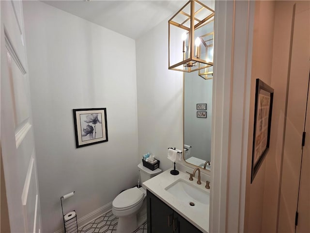 bathroom with vanity, a notable chandelier, toilet, and baseboards