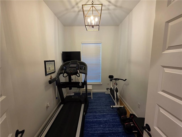 exercise room with a notable chandelier, baseboards, and dark colored carpet
