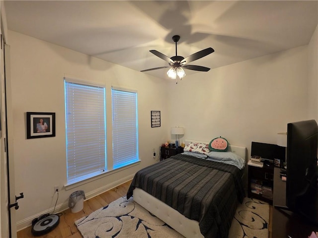 bedroom with ceiling fan, wood finished floors, and baseboards